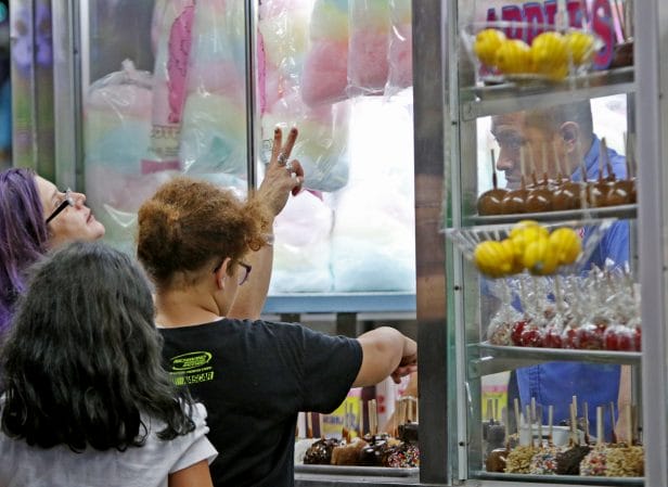 Fair patrons order cotton candy and caramel apples Wednesday night.