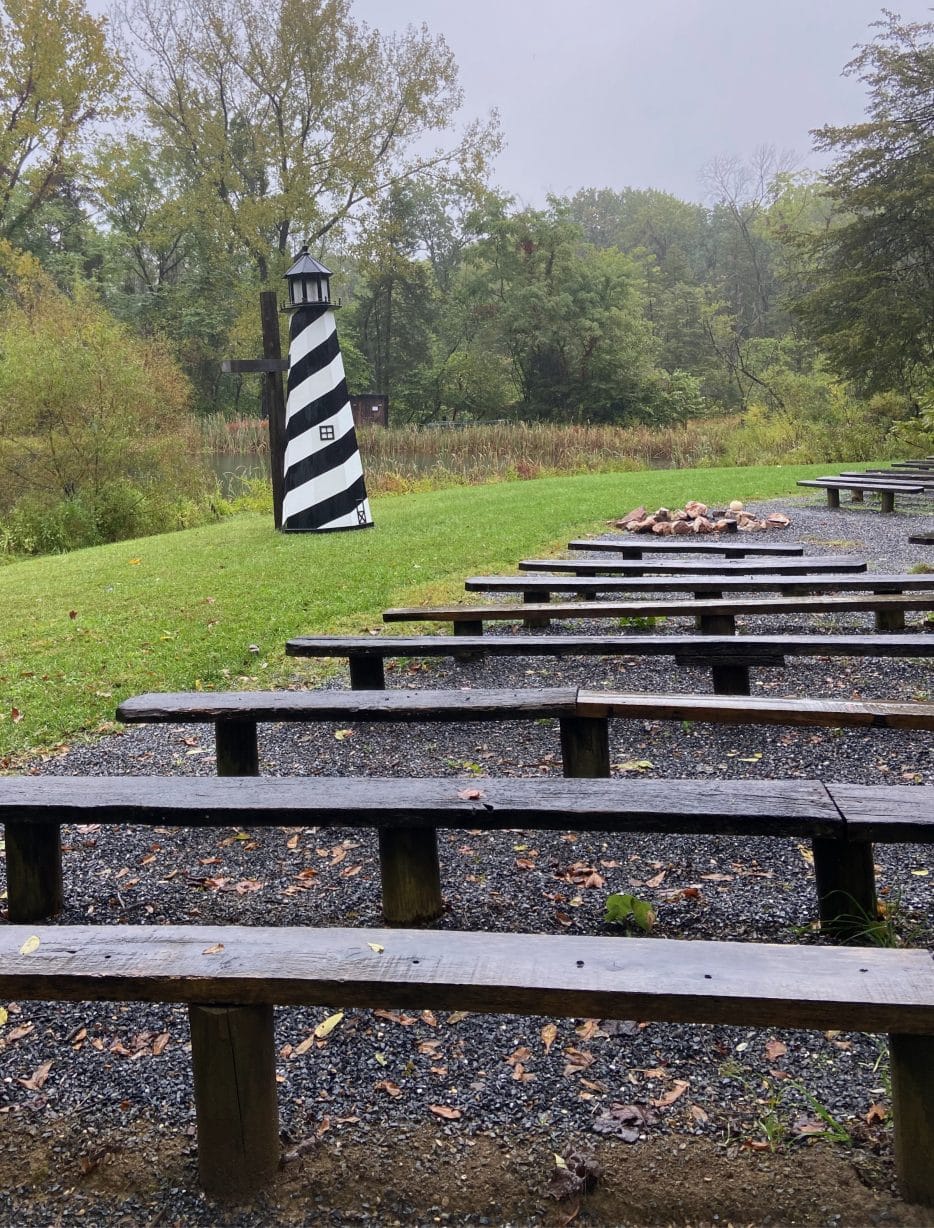 A replica lighthouse sits next to rain-soaked empty benches outside.