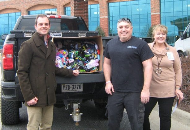 People smile in front of a pick-up truck with its bed full of donated socks