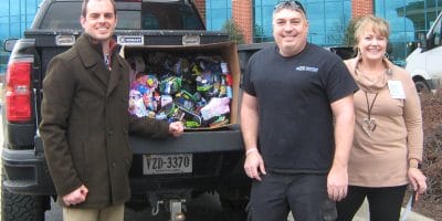 People smile in front of a pick-up truck with its bed full of donated socks