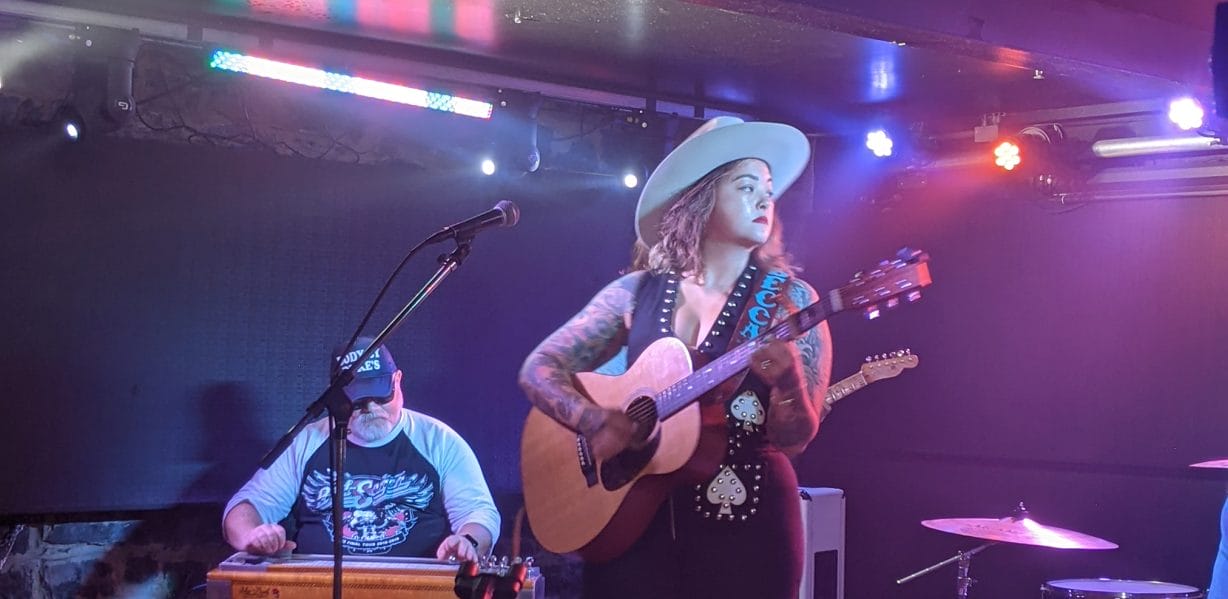 A woman with a guitar in front of a man on a keyboard