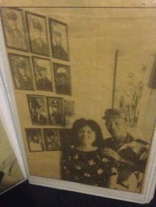 A photo of a yellowed newspaper with two people standing.