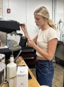 A woman rinses out a mug with steaming hot water