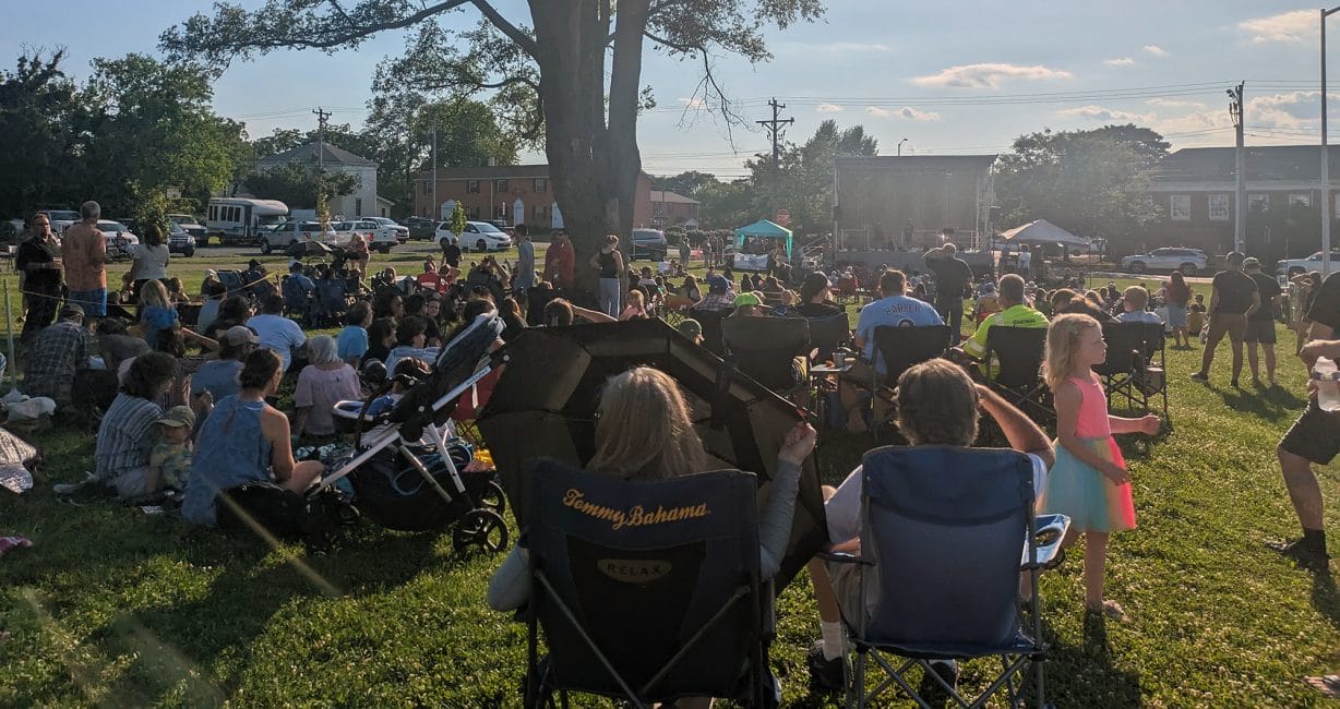 People sitting in lawn chairs and on blankets on the grass