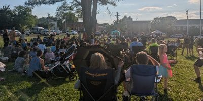 People sitting in lawn chairs and on blankets on the grass