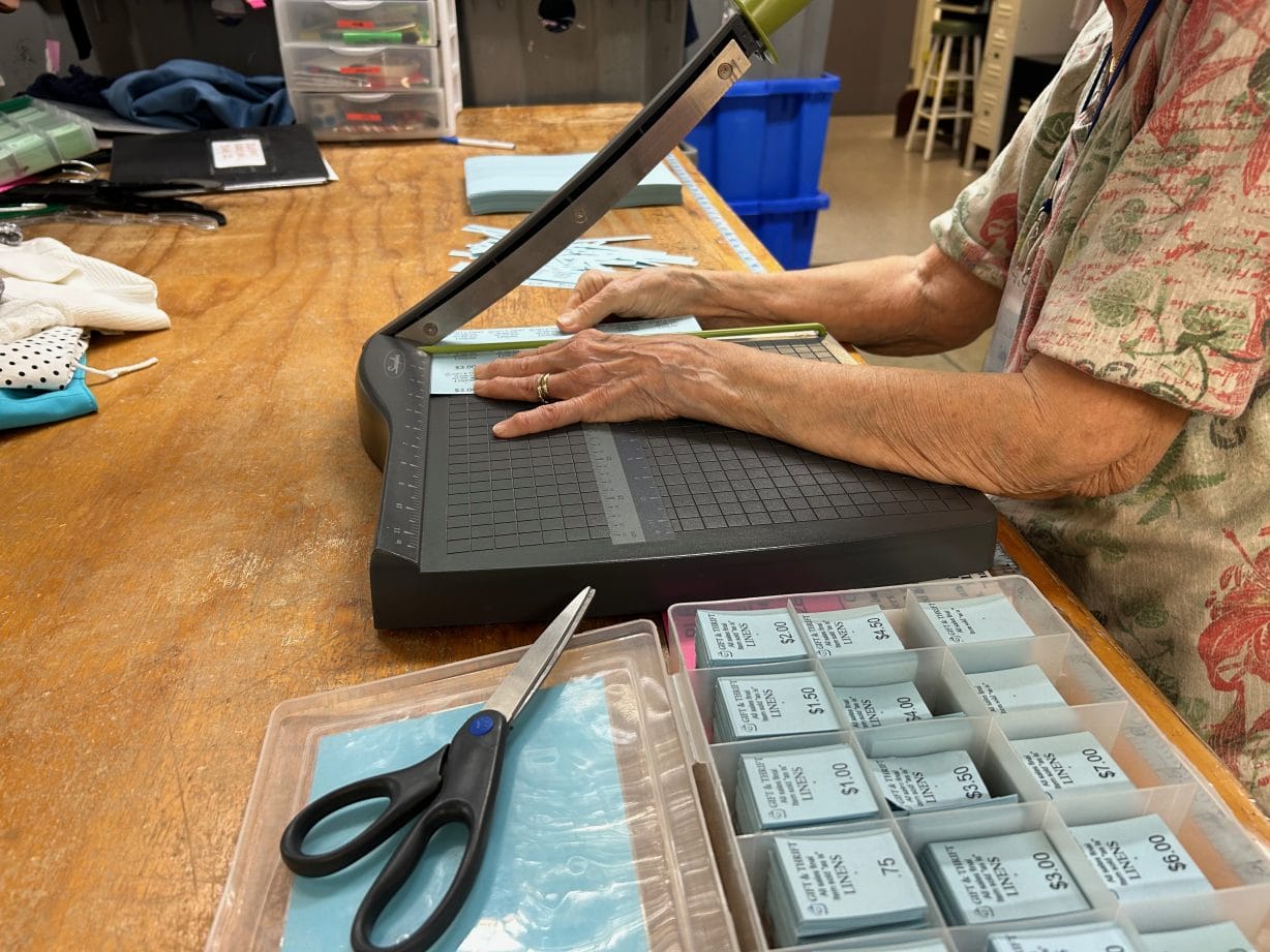 Hands holding a piece of paper in a paper-cutter.