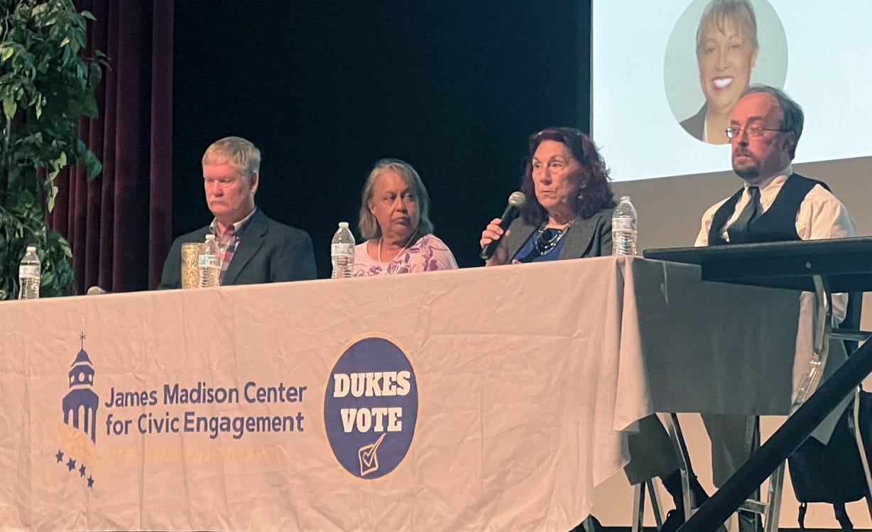 Four people with microphones sit at a table