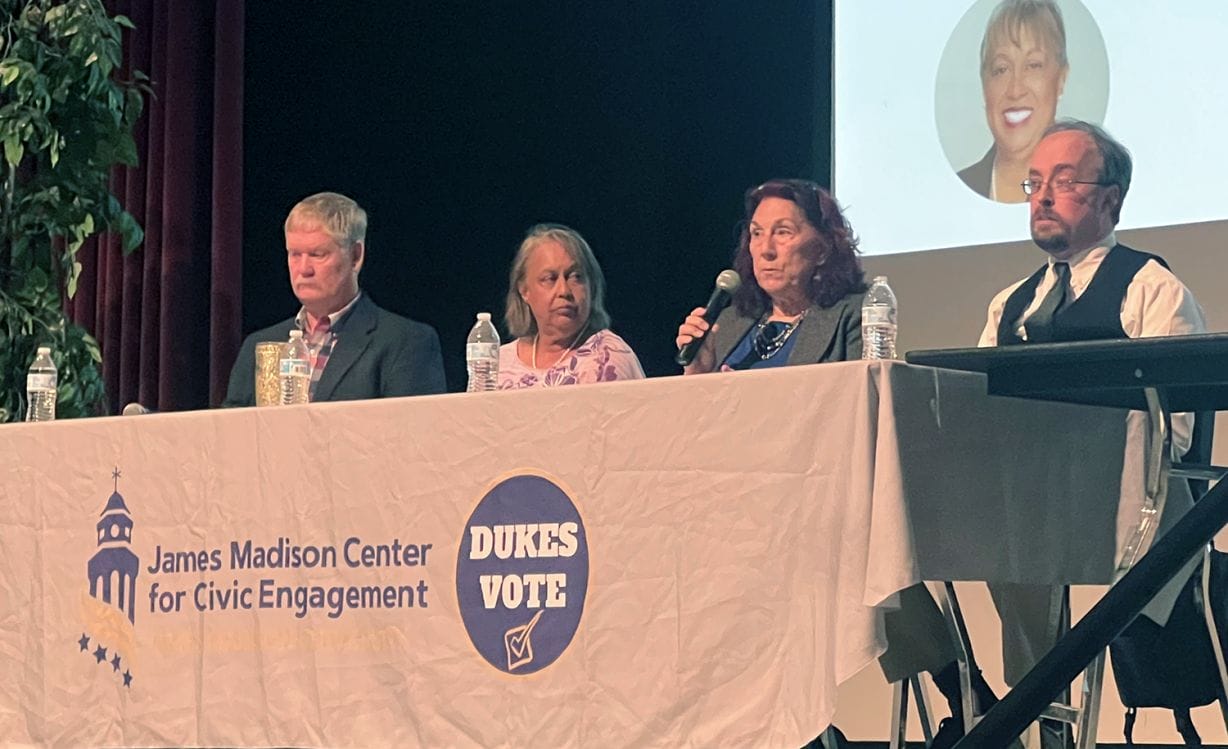 Four people with microphones sit at a table
