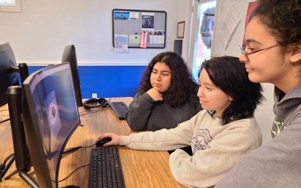 Three women look at a computer