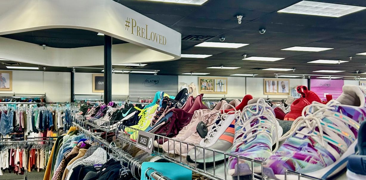 Shoes in the foreground and racks of clothing behind them