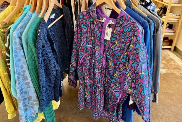 A purple windbreaker with multicolor shapes on a rack of clothes
