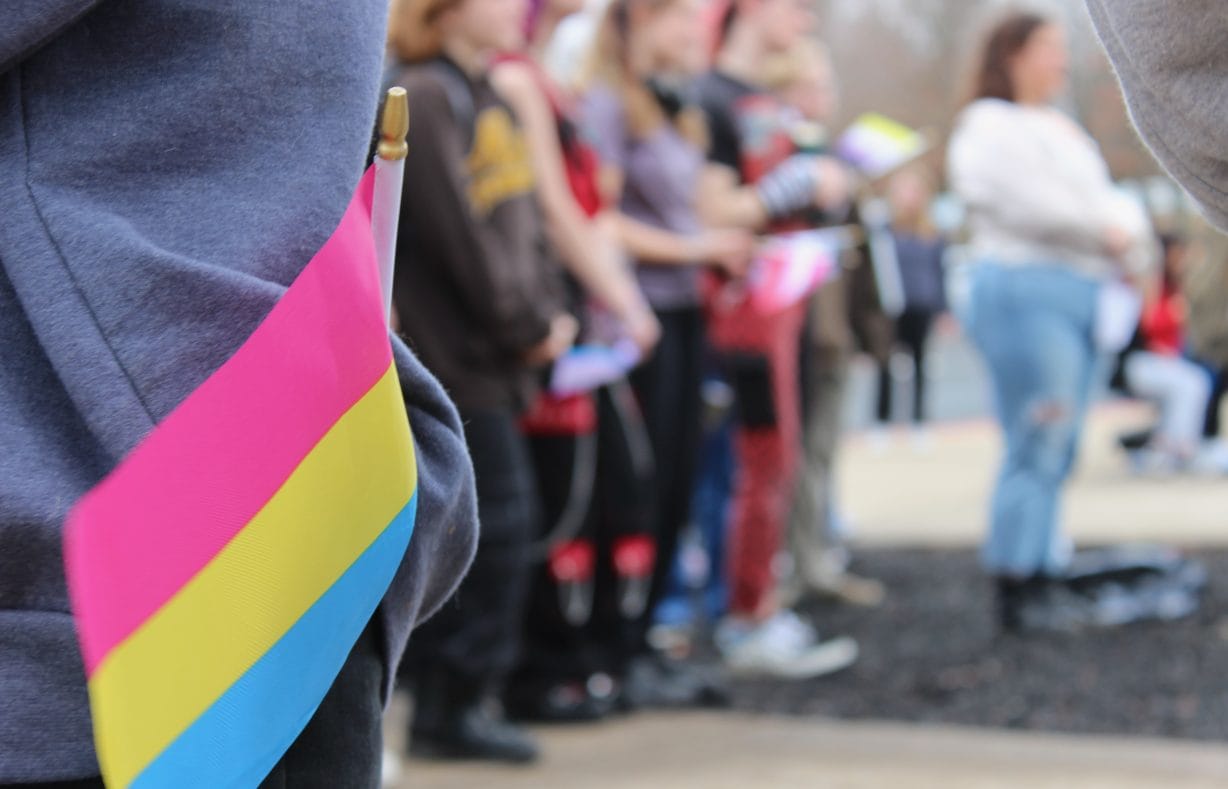 A colorful flag in the foreground and students watching in the background