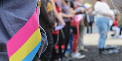 A colorful flag in the foreground and students watching in the background