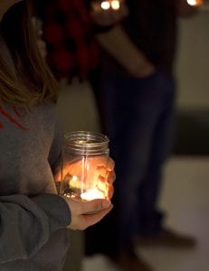 A woman's hands hold a glass jar with a light in it