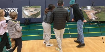 People standing in front of designs on easels