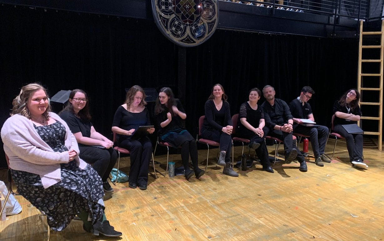 Nine people sitting on a stage