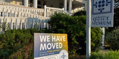 A sign saying "we have moved" outside an old, stately white house.