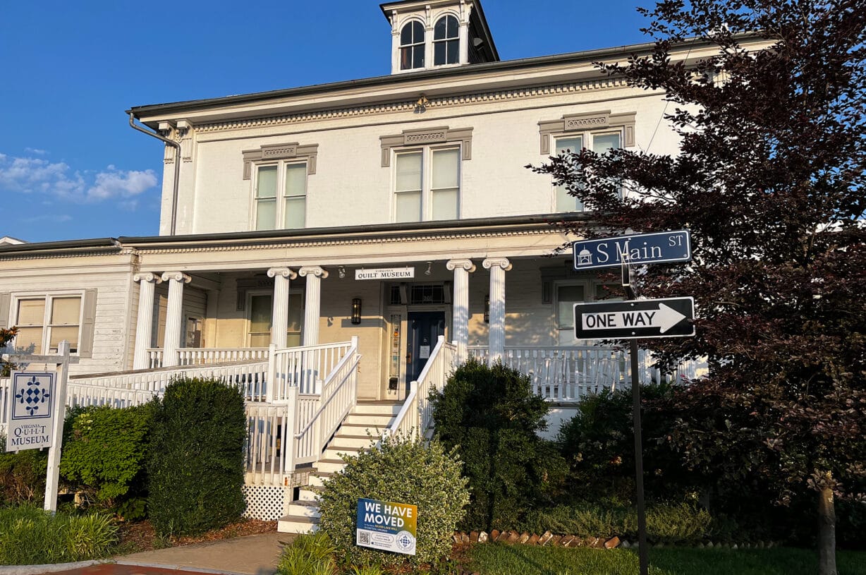 A two-story white painted house with columns on the front porch.