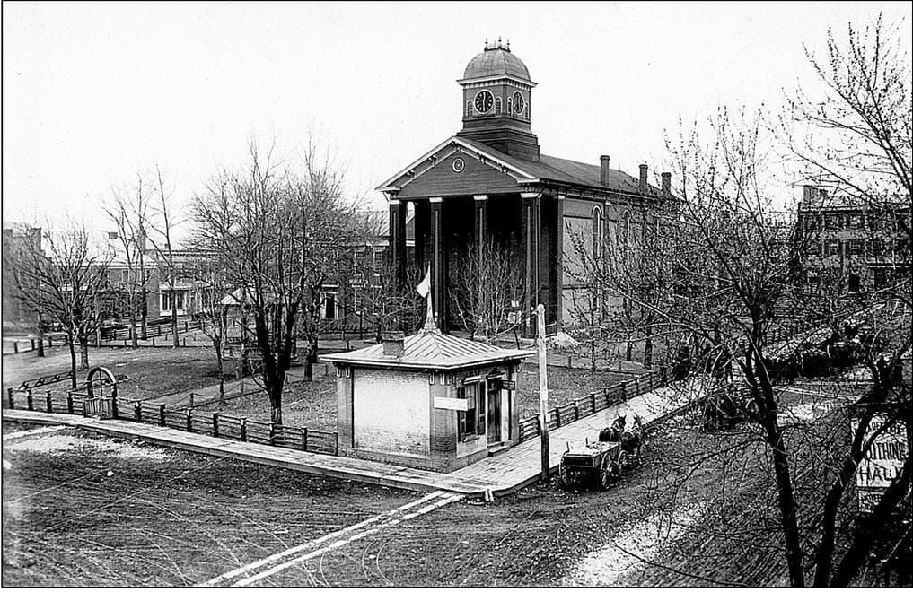 A black-and-white image of courthouse and a horse and buggy driving past it