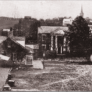 A black-and-white photo of old houses connected by a dirt road