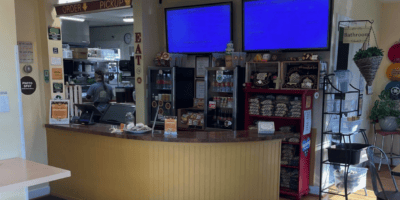 A lunch counter, menu board and peak into the kitchen where an employee is preparing an order