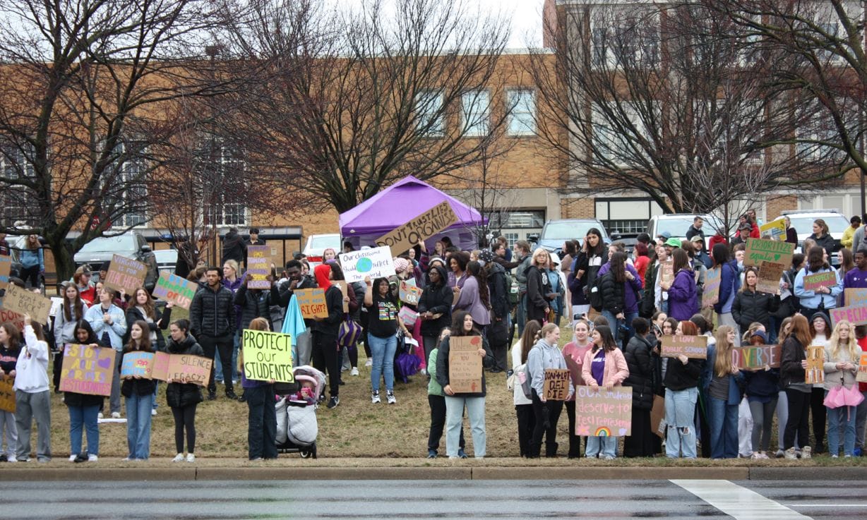 people holding signs and umbrellas along the road