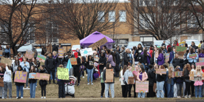 people holding signs and umbrellas along the road