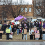 people holding signs and umbrellas along the road