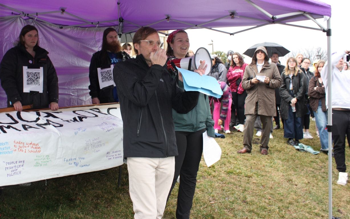 A man talks to protesters with signs