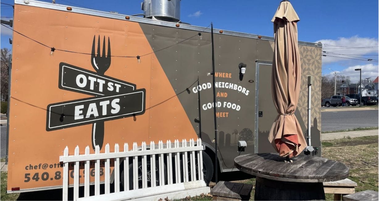 A food truck trailer next to a picnic table