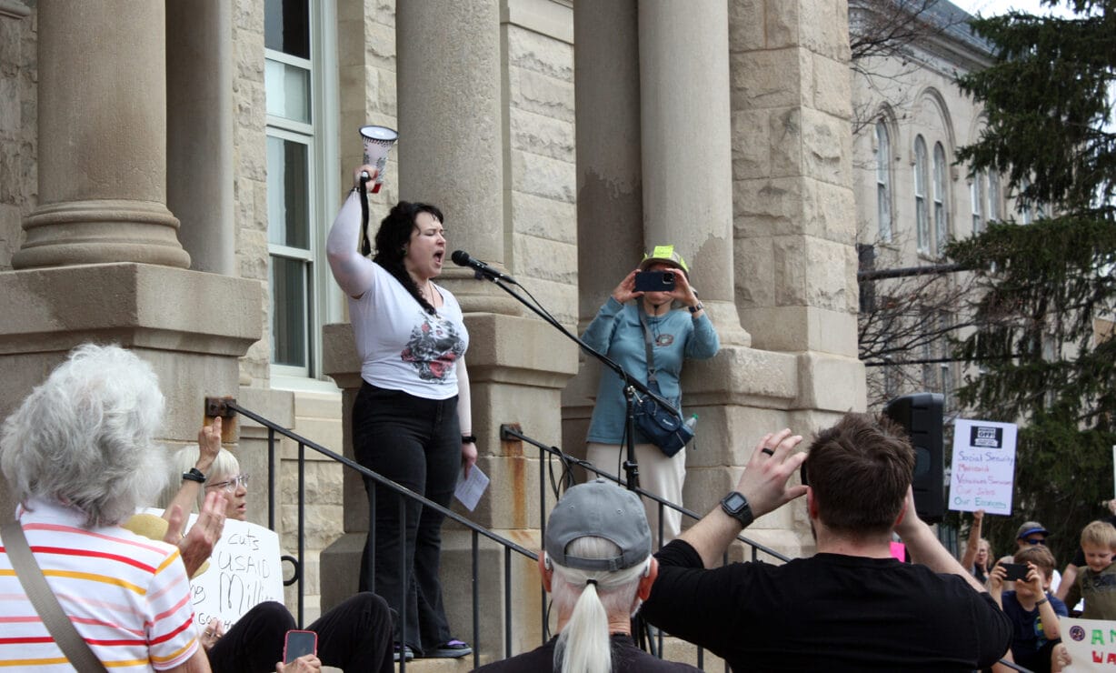 A woman holding a megaphone speaks to a crowd of protesters