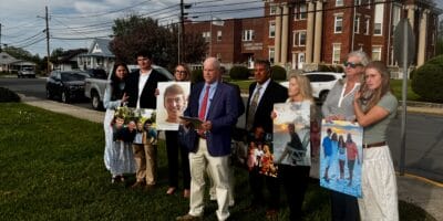 A group of people holding large photos in front of a courthouse
