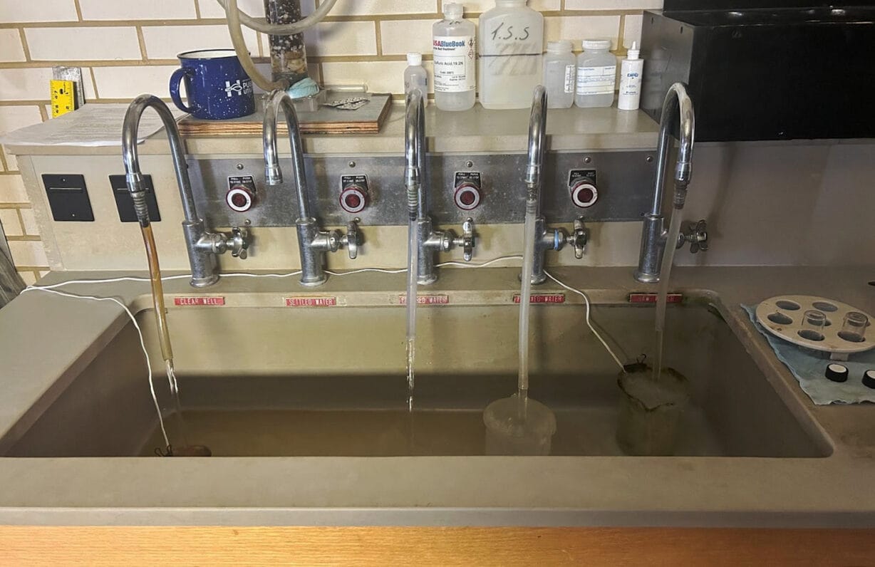 five individually labeled faucets run water into a sink for testing 