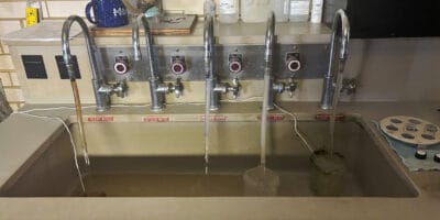 five individually labeled faucets run water into a sink for testing
