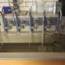 five individually labeled faucets run water into a sink for testing