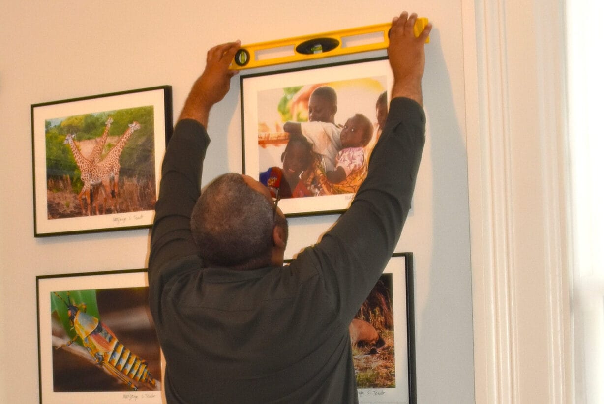 A man holding a level checks whether a portrait frame is straight