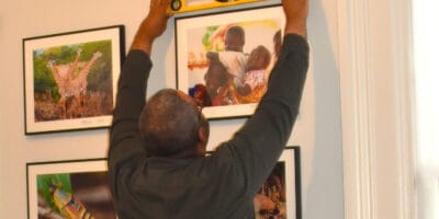 A man holding a level checks whether a portrait frame is straight