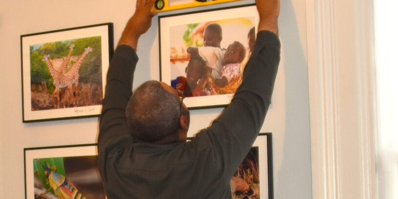 A man holding a level checks whether a portrait frame is straight