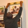 A man holding a level checks whether a portrait frame is straight