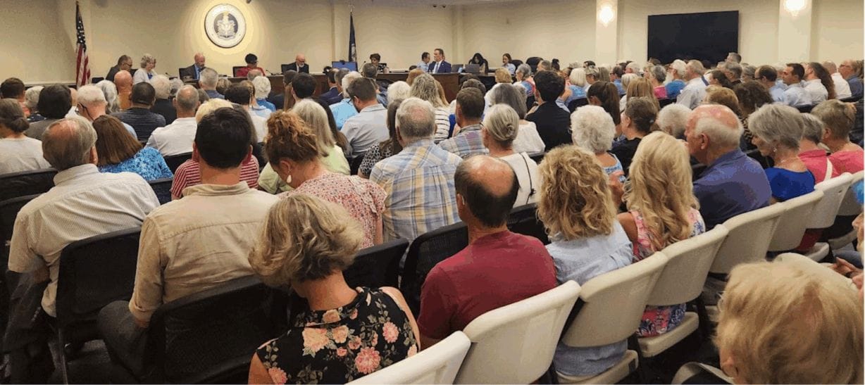 rows of chairs with people in every one in the city council chambers