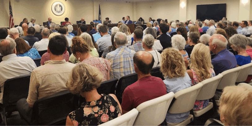 rows of chairs with people in every one in the city council chambers