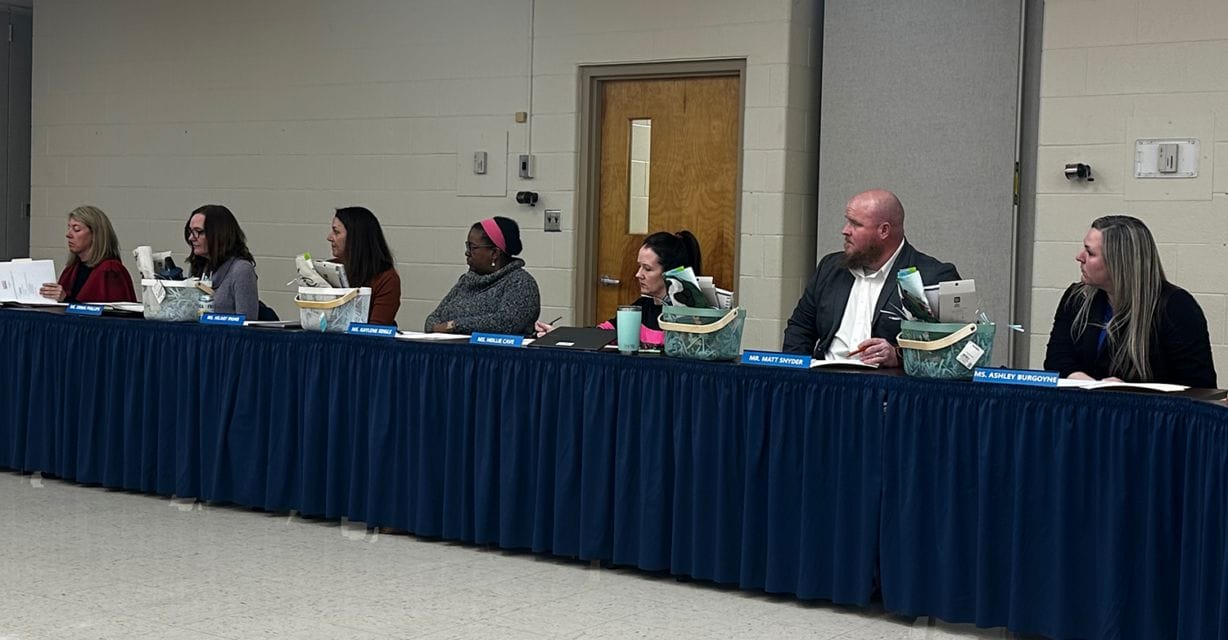 Seven people sit at a long table