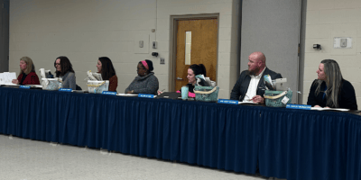 Seven people sit at a long table