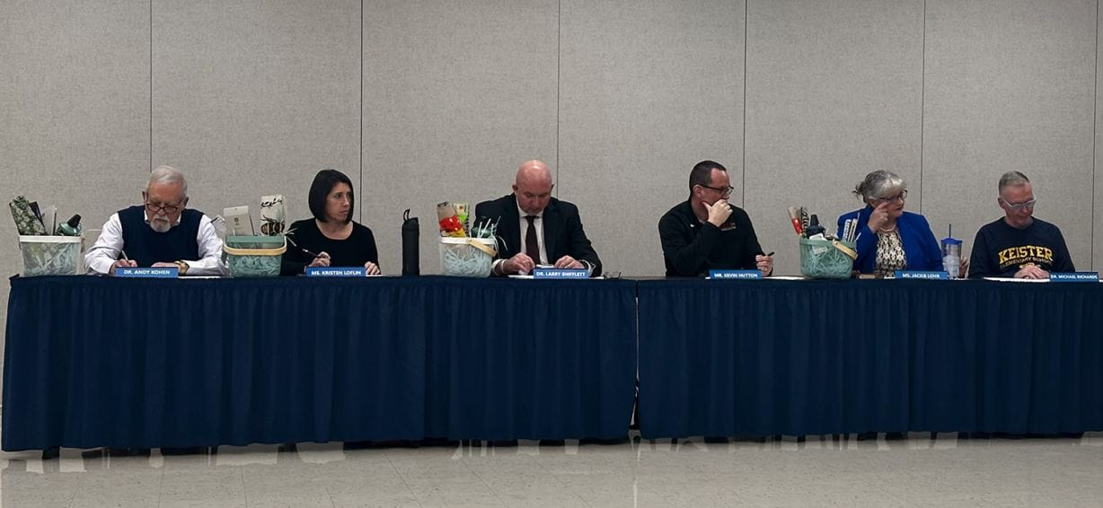 Six people sit at a long table