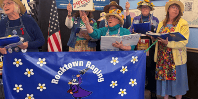 Women holding signs saying "Impeach" while singing.