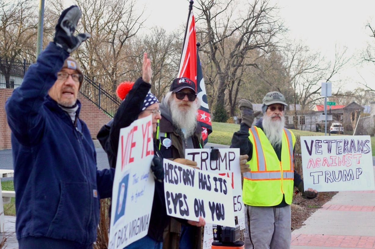 Four people with flags and signs 